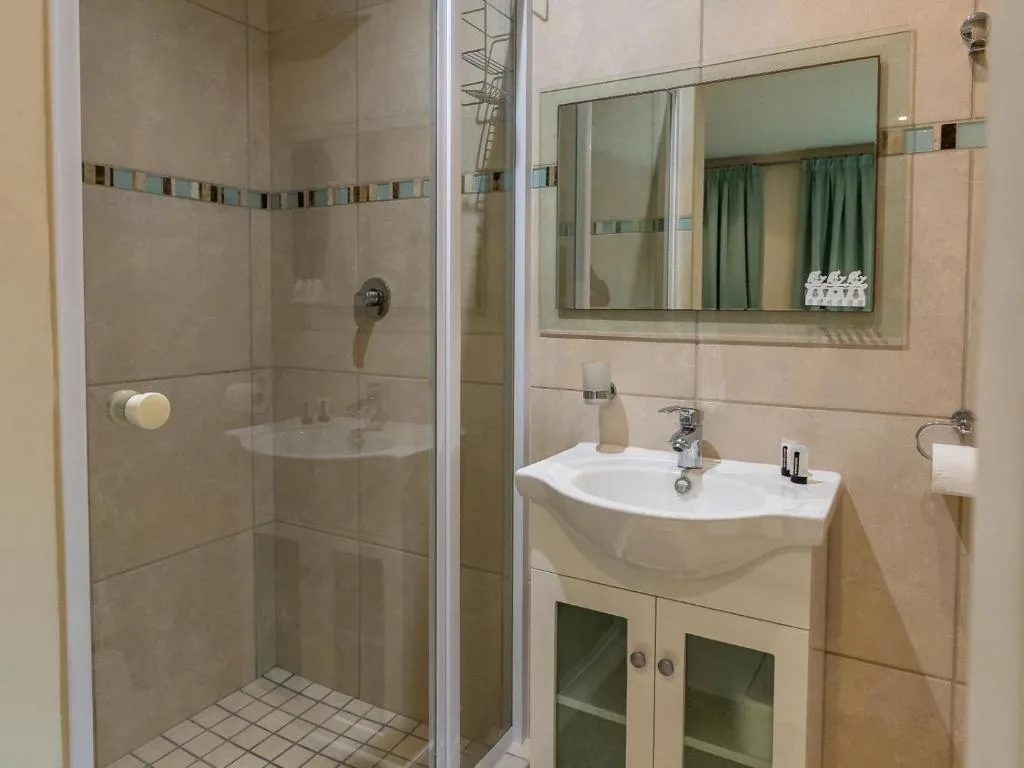 Modern bathroom with glass shower enclosure, curved white sink, and framed mirror