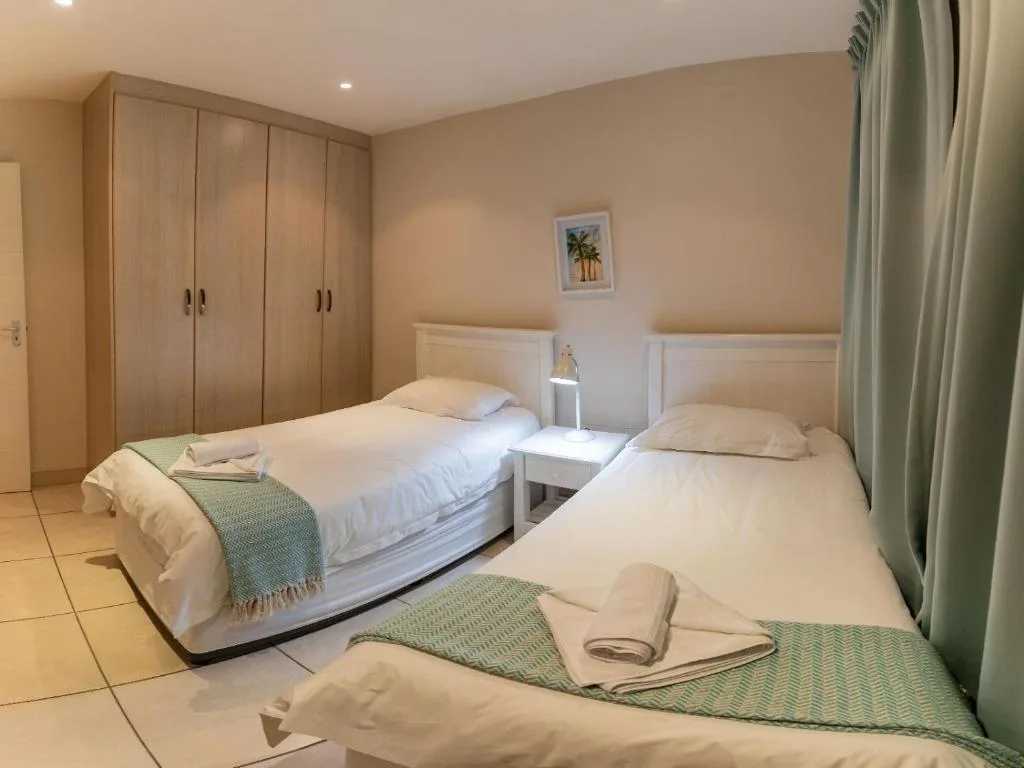 Twin bedroom with white linens, wooden wardrobes, and neutral decor