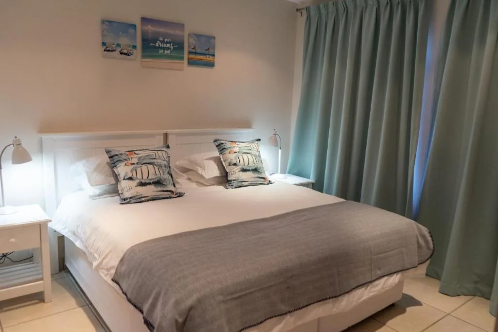 Bright bedroom with queen bed, coastal artwork, and mint curtains