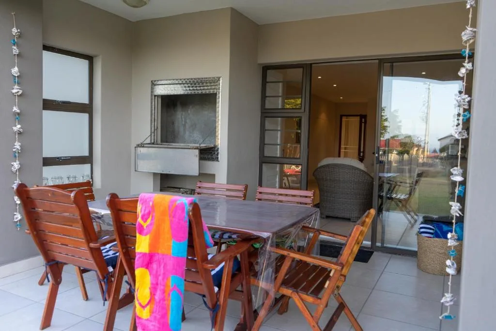 Indoor dining area with wooden table, chairs, and garden view through glass doors