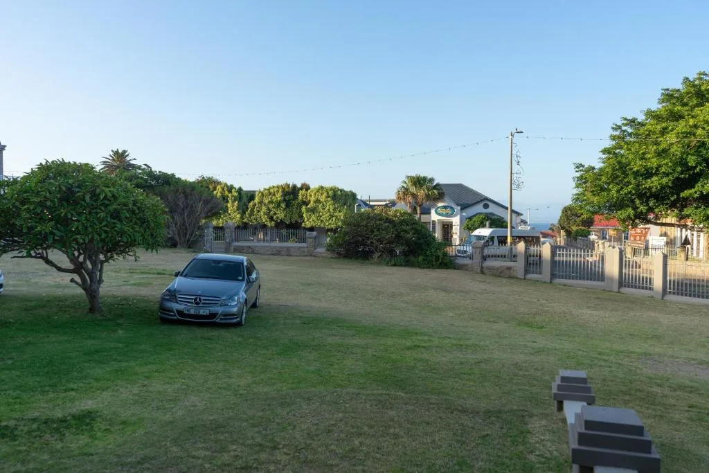 Spacious garden with parked car, established trees, and gated residential properties