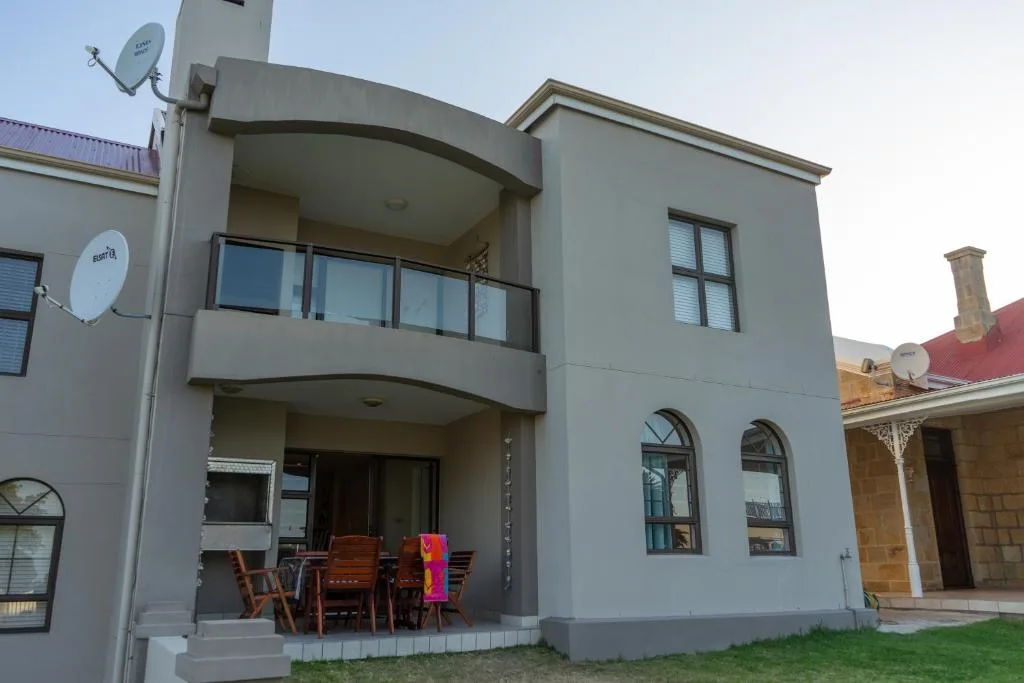 Modern grey apartment building with covered patio and dining furniture
