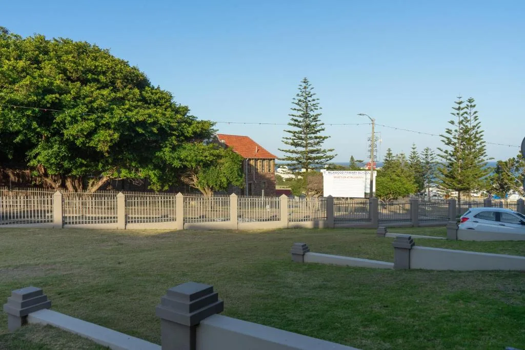 Property entrance with white fence gate and manicured lawn surroundings