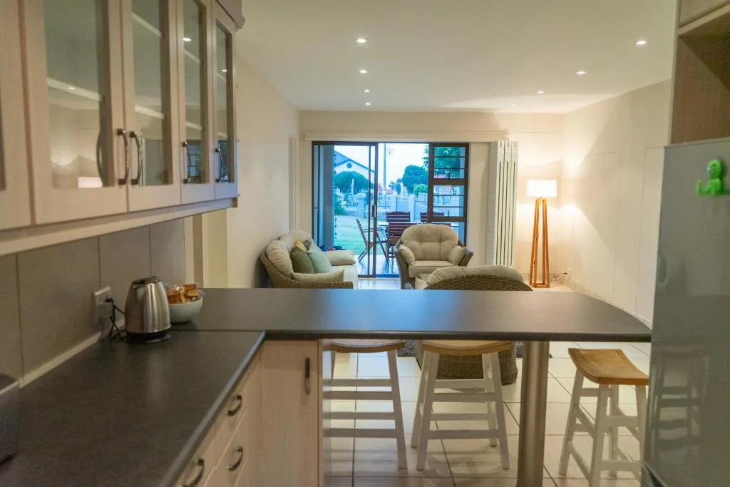 Modern kitchen with island counter and bar seating, opening to lounge area