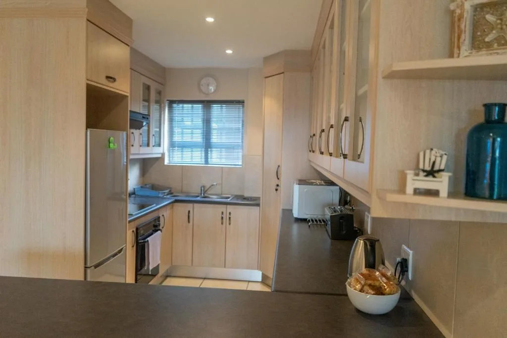 Modern kitchen with light wood cabinetry, stainless steel appliances, and granite countertops