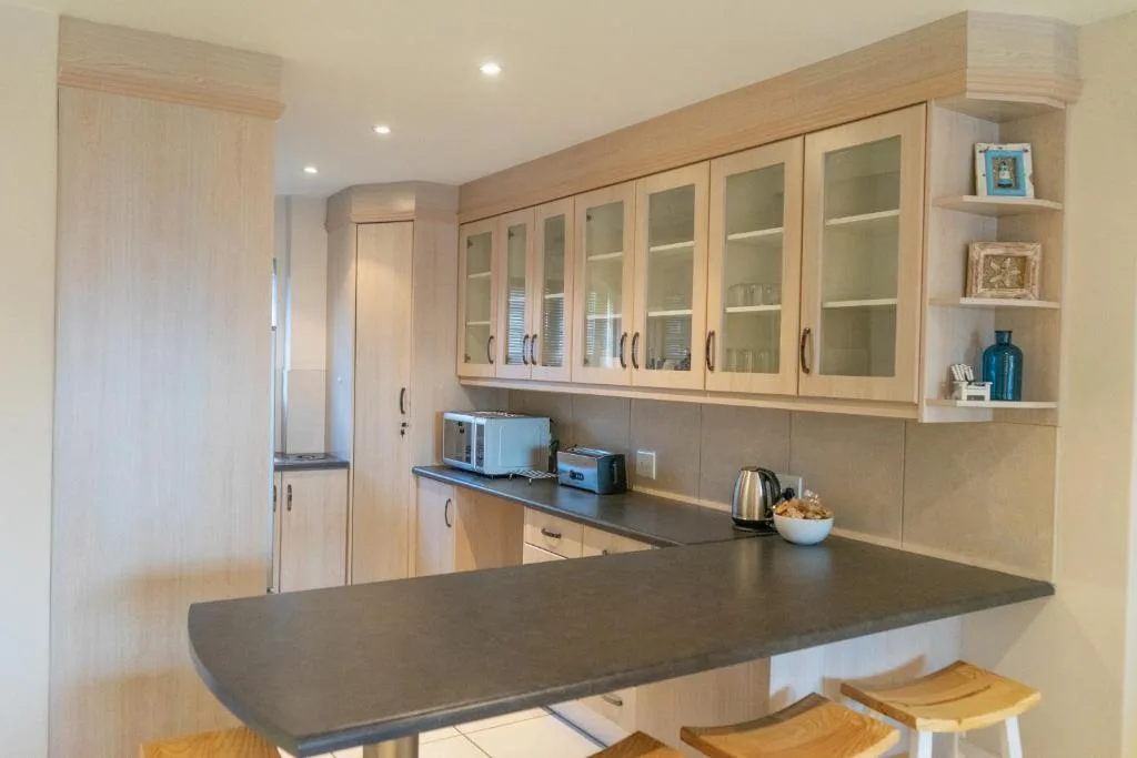 Modern kitchen with light wood cabinets, dark countertop, and bar seating
