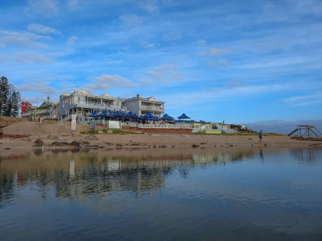 Beachfront property with ocean, sand, and blue sky vista