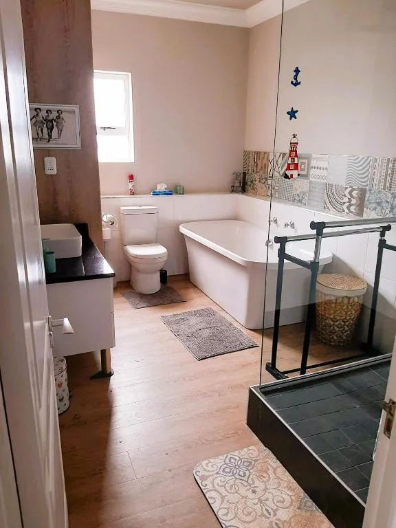 Spacious bathroom with freestanding bathtub, toilet, shower enclosure, and nautical decor
