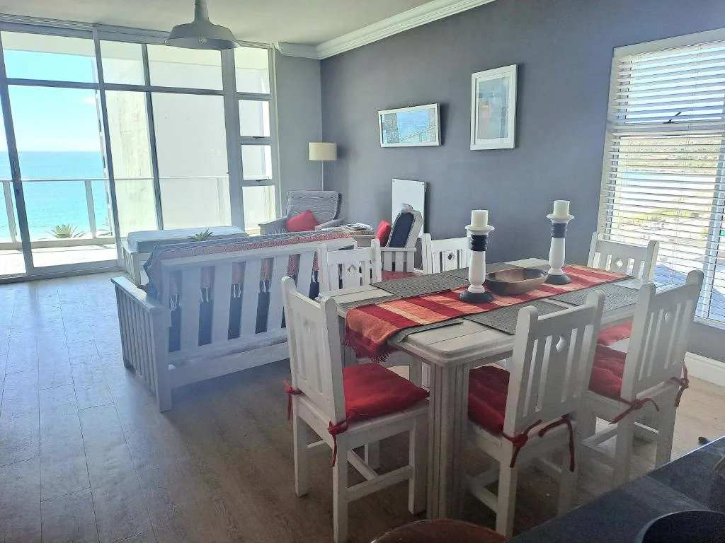 Dining area with white wooden chairs and table, ocean view through large windows