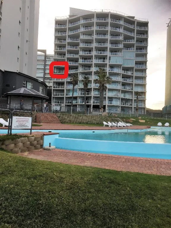 Bright blue swimming pool with lawn and apartment building backdrop
