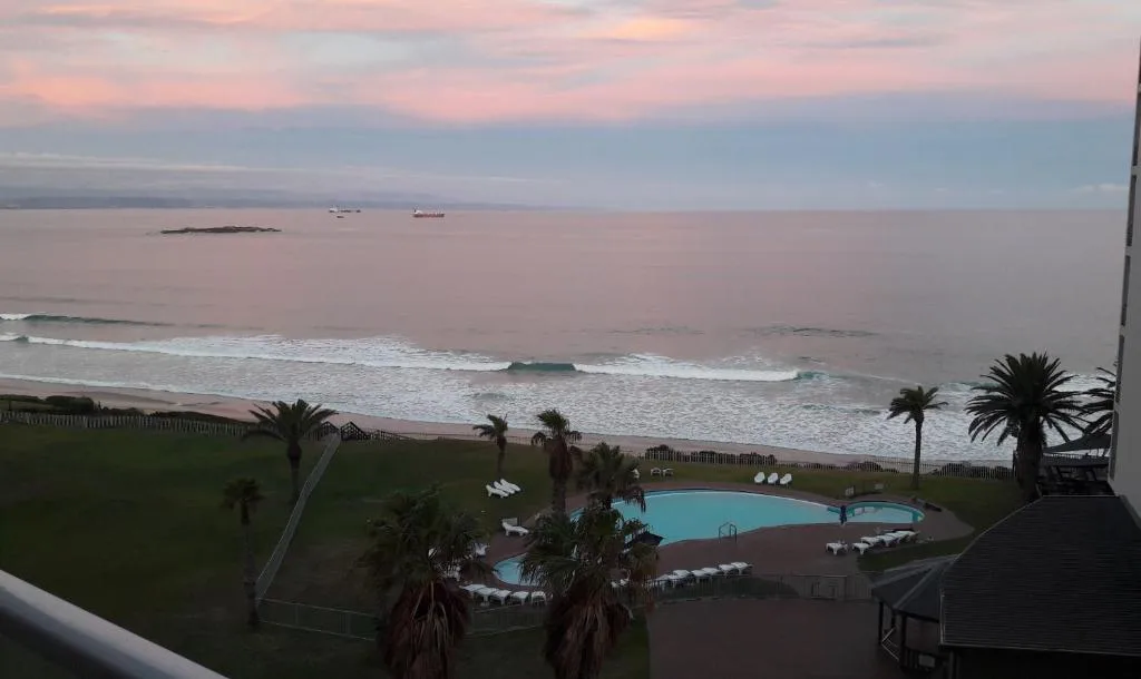 Sunset ocean view with beach, pool, and palm trees from apartment