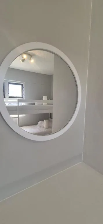 Modern round mirror above white vanity in bright bathroom space