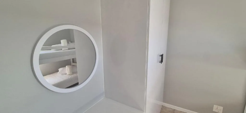 Modern round mirror above white vanity in bright bathroom