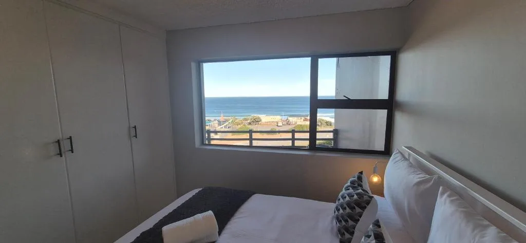 Bright bedroom with ocean view through large windows and balcony