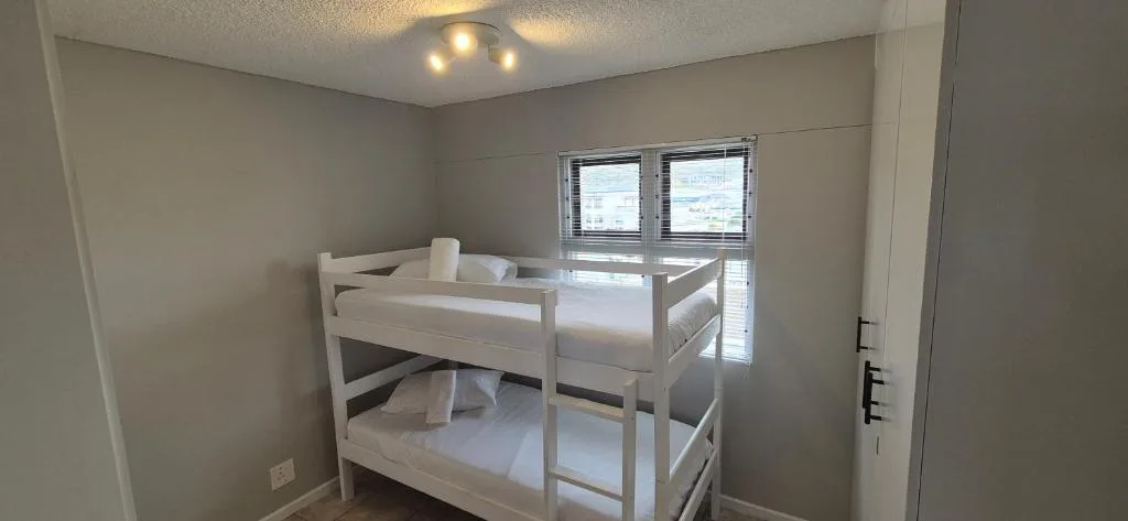 Bright bedroom with white bunk bed and sliding glass doors to balcony