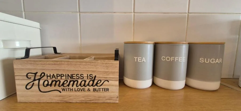 Kitchen counter with homemade sign and labeled storage containers for tea, coffee, and sugar