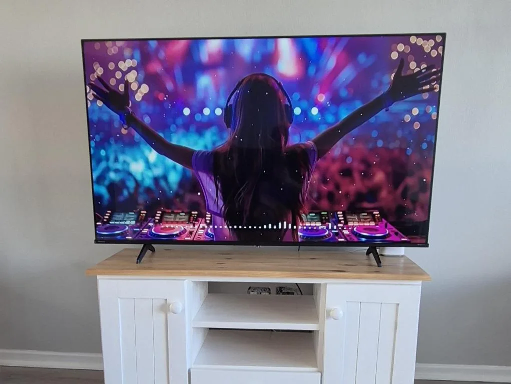Flat-screen television on white wooden entertainment unit displaying colorful concert visuals