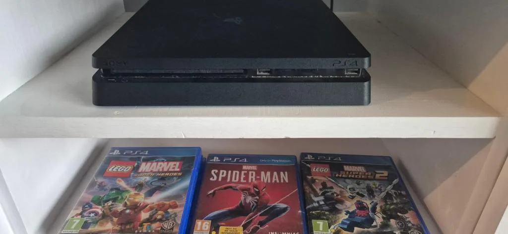 PlayStation console and video game collection displayed on white shelving