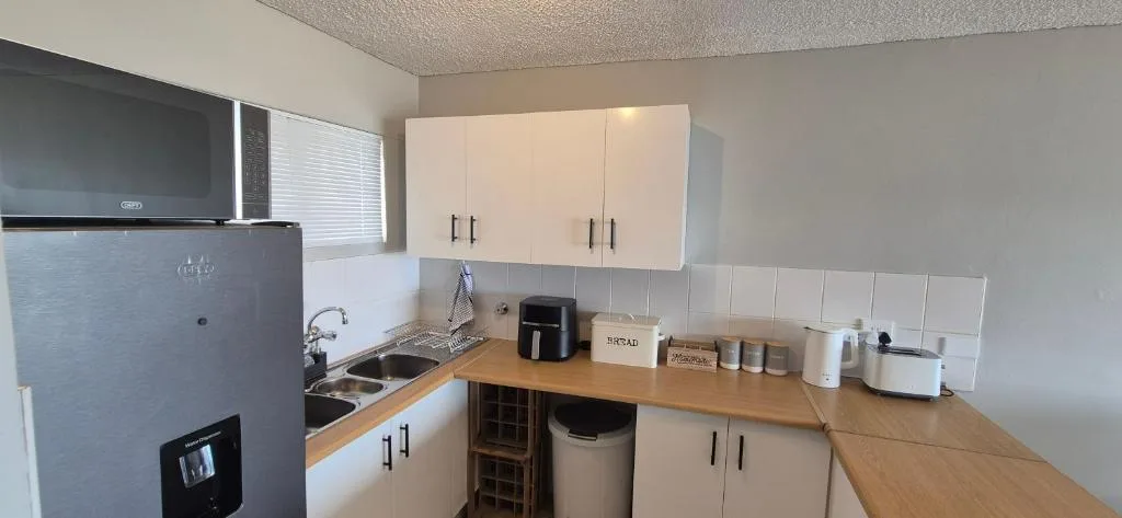 Compact kitchen with wooden counters, white cabinetry, and stainless steel appliances