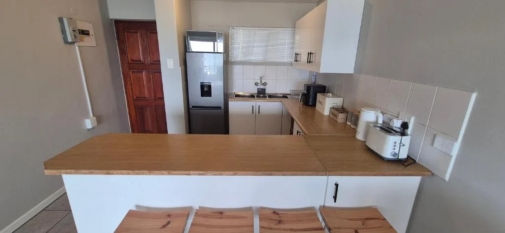 Open-plan kitchen with wooden counters, stainless steel fridge, and bar seating