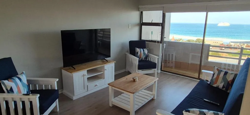 Bright lounge with TV, wooden furniture, ocean view through glass doors