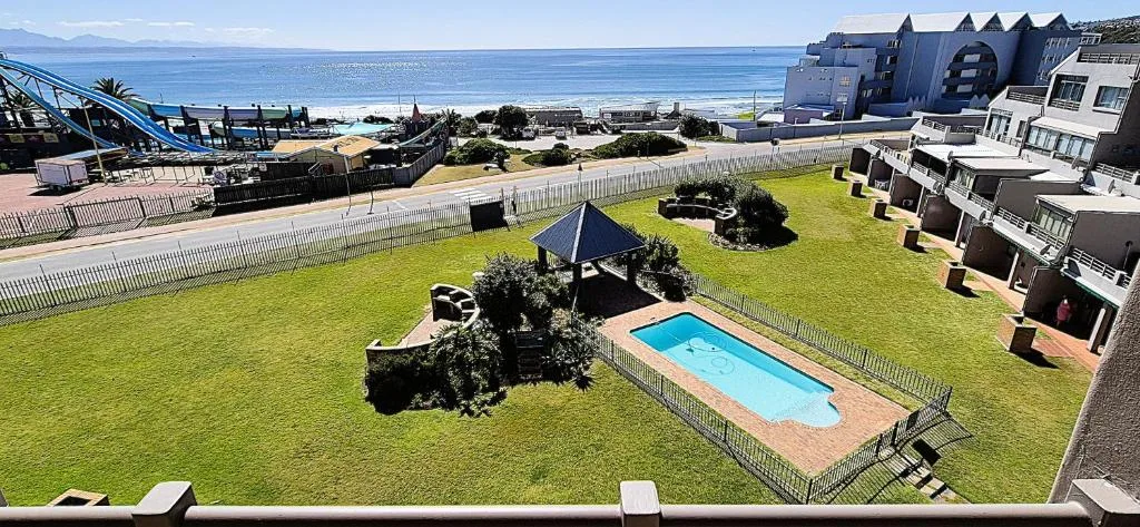 Rectangular swimming pool in manicured garden with ocean view beyond