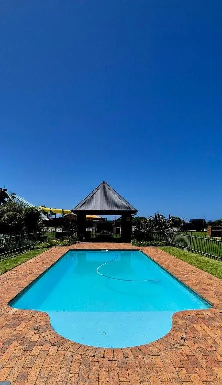 Bright blue swimming pool with brick surround and modern house backdrop