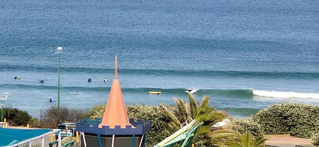 Ocean beach with surfers and waves visible from property deck