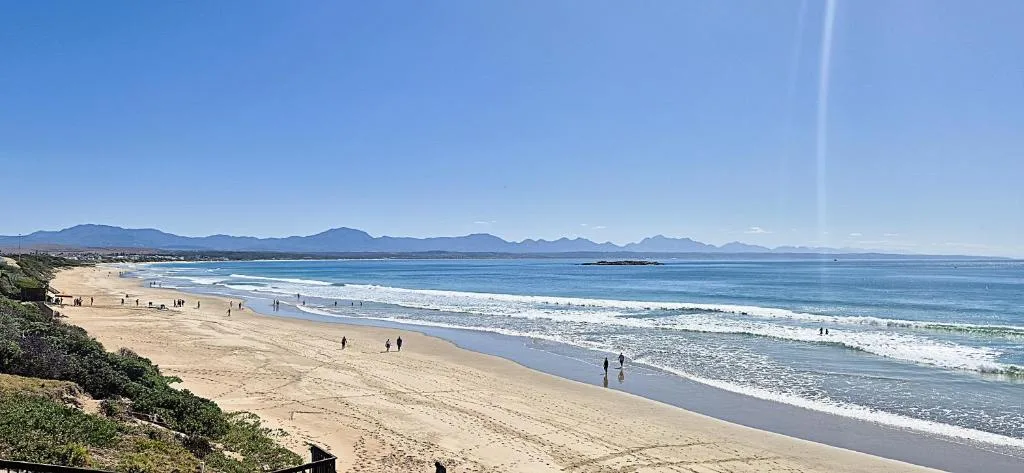 Pristine beach with mountains and ocean vista in bright sunlight