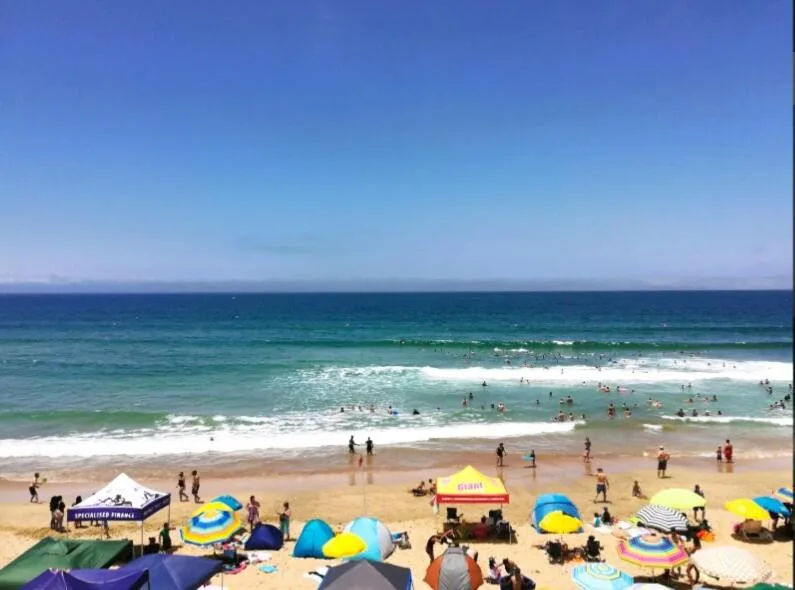 Scenic coastal beach view with ocean, sand, and swimmers enjoying the water
