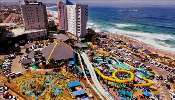 Aerial beachfront view with ocean, beach, and colorful water park below