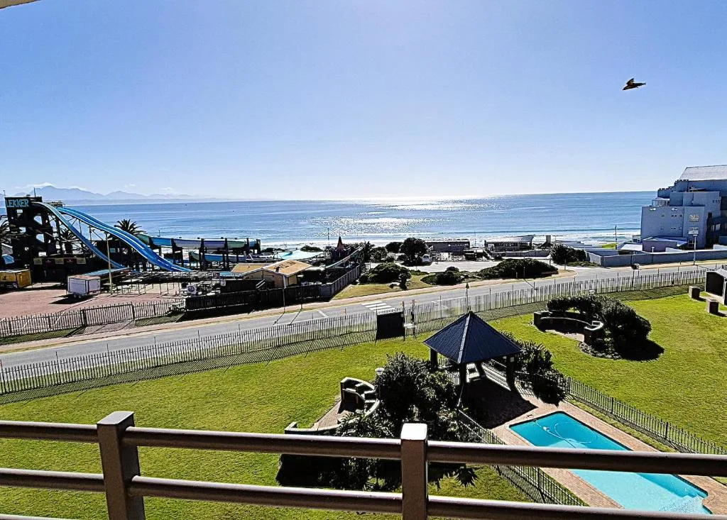Scenic coastal view with ocean, mountains, and manicured garden grounds