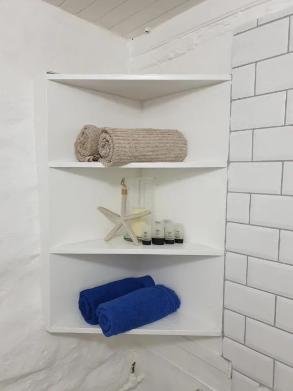 Bathroom shelving with rolled towels, toiletries, and decorative starfish