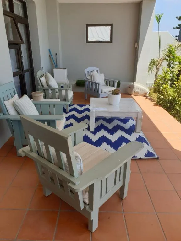Outdoor patio with white wooden chairs and blue chevron rug