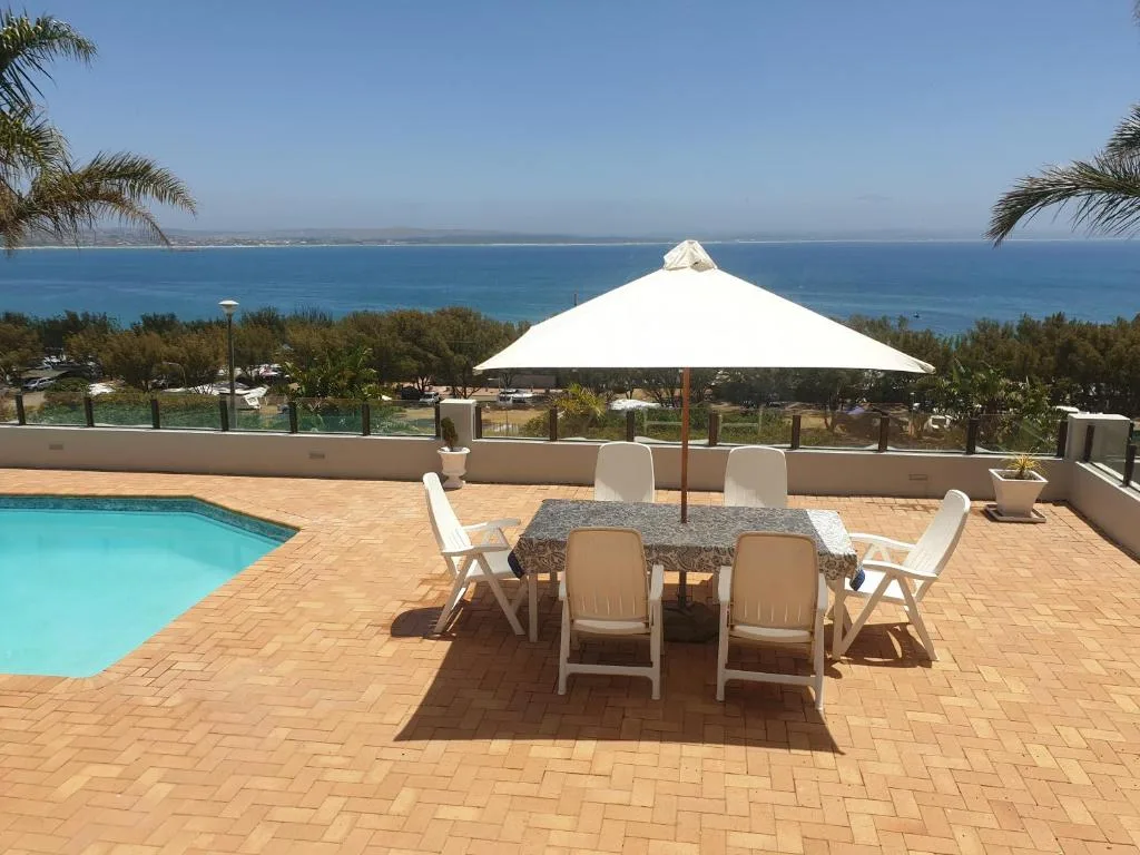 Oceanview patio with pool, dining table, umbrella, and lounge chairs