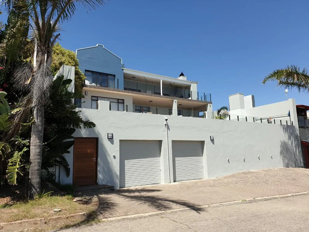 Modern white multi-story house with double garage and palm trees