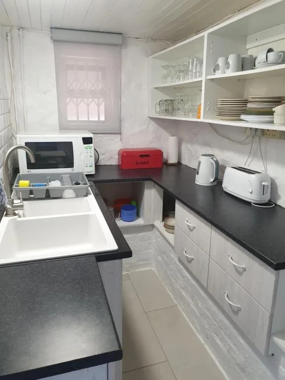 Compact kitchen with black countertops, white cabinetry, and open shelving