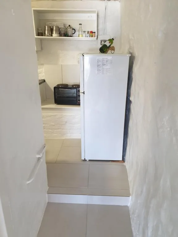 Compact kitchenette with white refrigerator and open shelving above