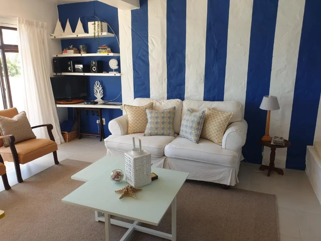 Bright lounge with cream sofa, blue striped accent wall, and coastal decor