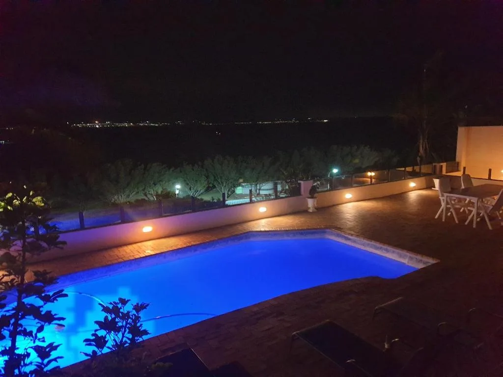 Illuminated swimming pool at night with ambient deck lighting and countryside views