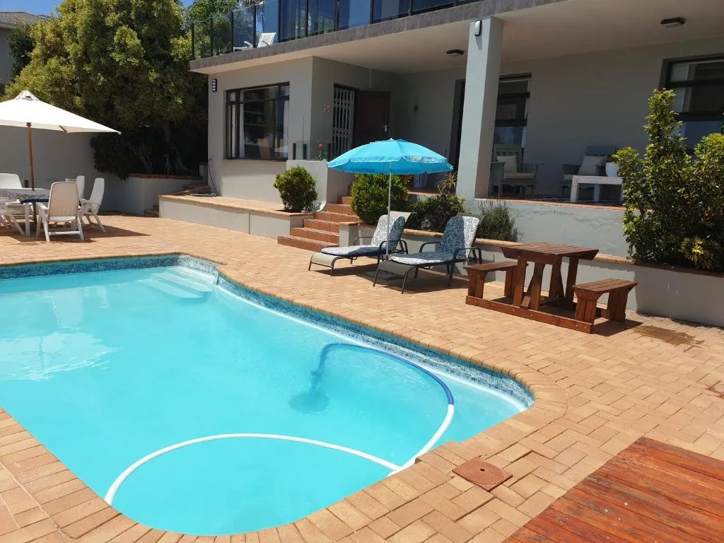 Inviting swimming pool with loungers, umbrellas, and modern house beyond