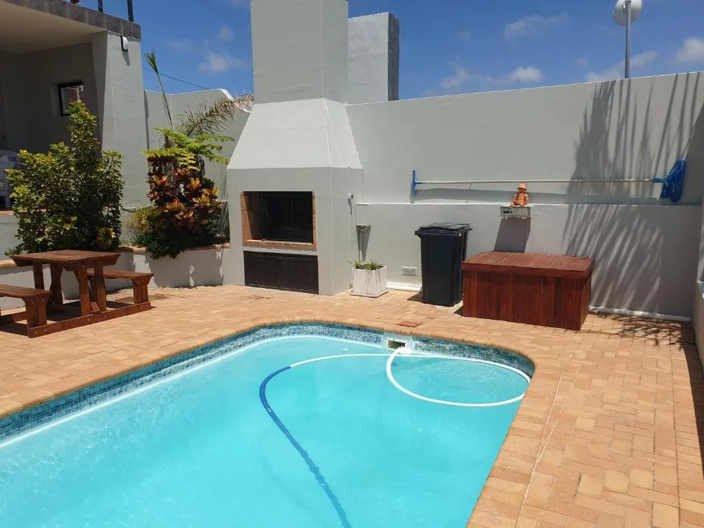 Bright turquoise swimming pool with brick patio and braai area