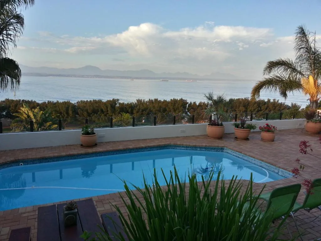Sparkling blue swimming pool overlooking ocean and mountains from terrace