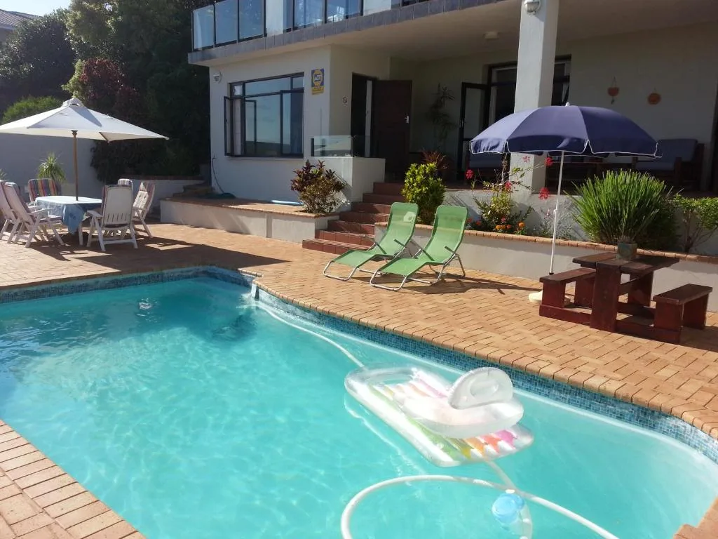 Sparkling swimming pool with loungers and umbrellas on brick patio