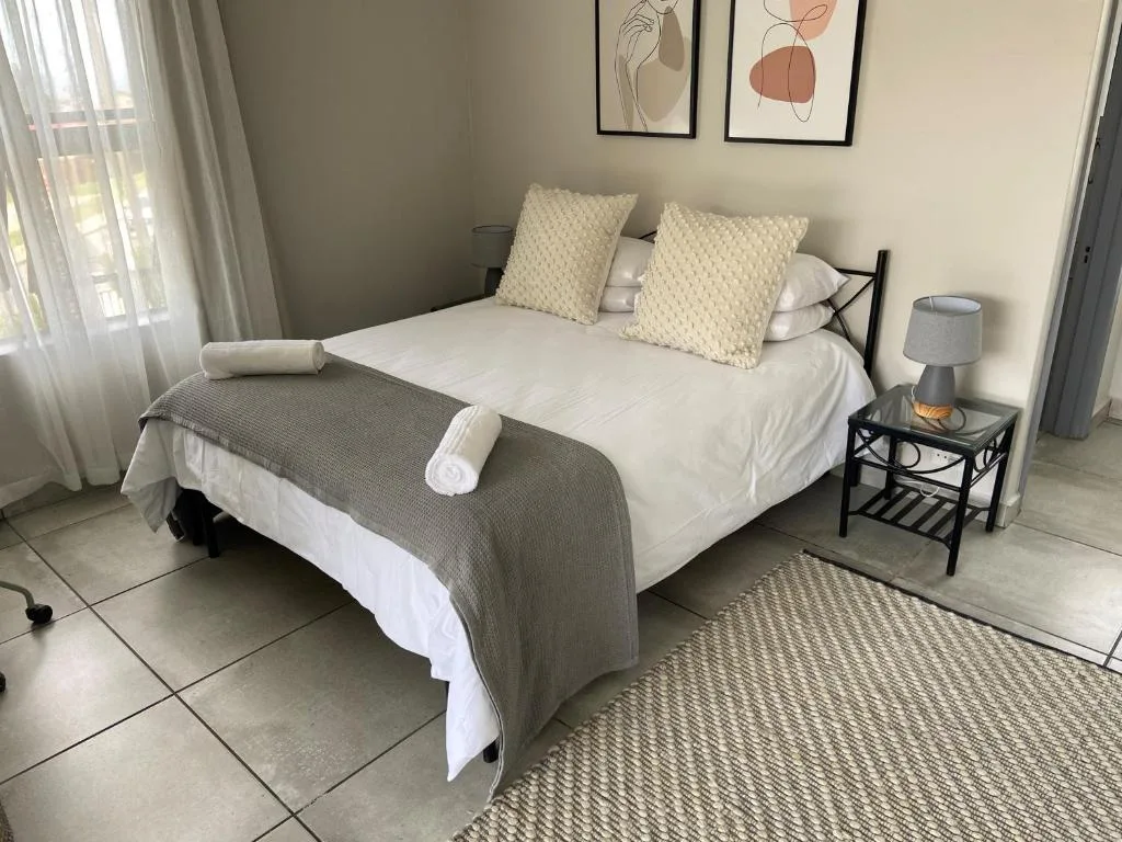 Bright bedroom with double bed, cream pillows, and modern wall art