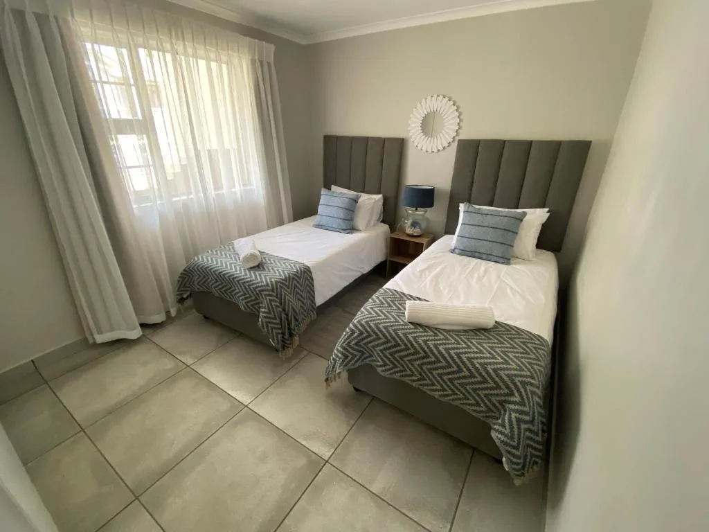 Twin bedroom with olive headboards, white bedding, and natural light from patio doors