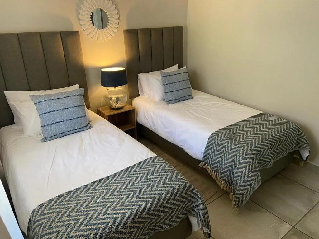 Twin bedroom with upholstered headboards, white bedding, and patterned throws
