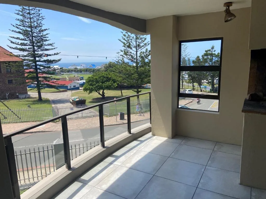 Covered balcony with ocean and town views, metal railing, tiled flooring