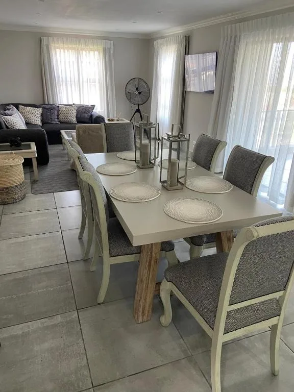 Modern dining table with cream chairs and place settings, open-plan living space