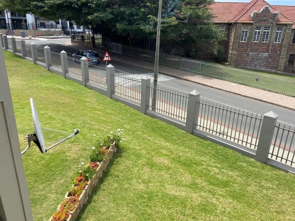 Property entrance with manicured lawn, modern fencing, and brick heritage building